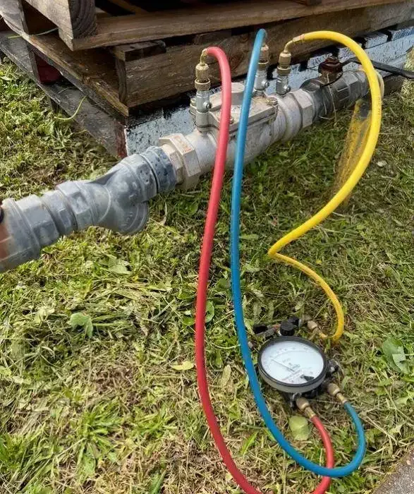 Backflow test kit gauge connected to a backflow preventer during a backflow test