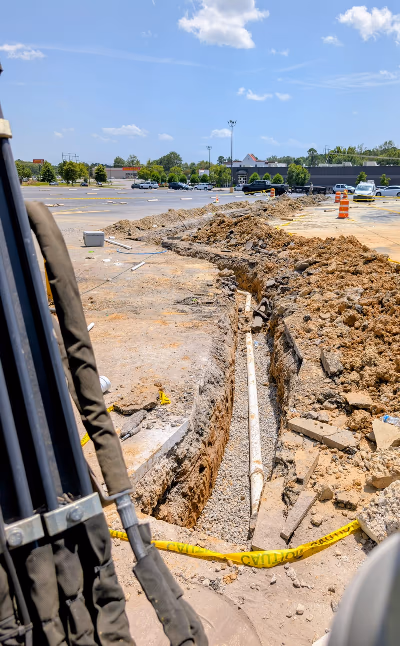 Grease trap sewer line installation in a parking lot trench for a new restaurant opening near UALR