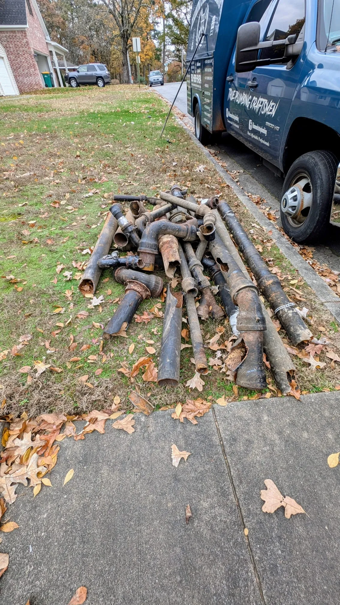 Old rusted pipes removed during a full replumb, piled on the lawn outside a Cammack Village home
