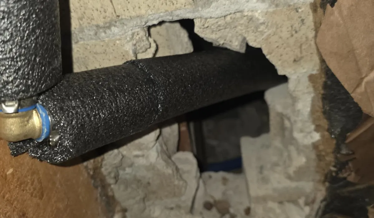 Foam-insulated water line routed through a block foundation to protect against freezing