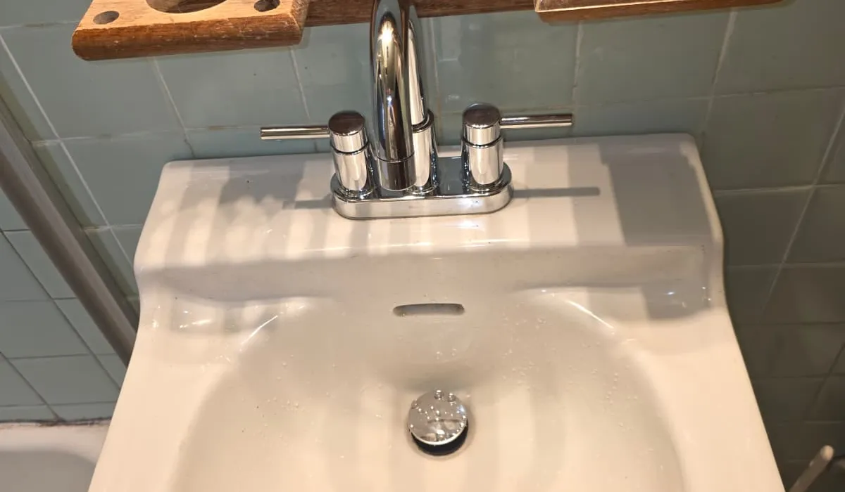 Wall-mounted bathroom sink with a new chrome faucet installed