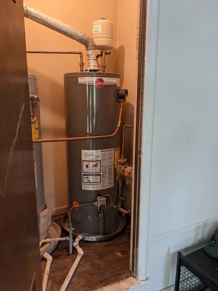Tank water heater with an expansion tank installed in a utility closet