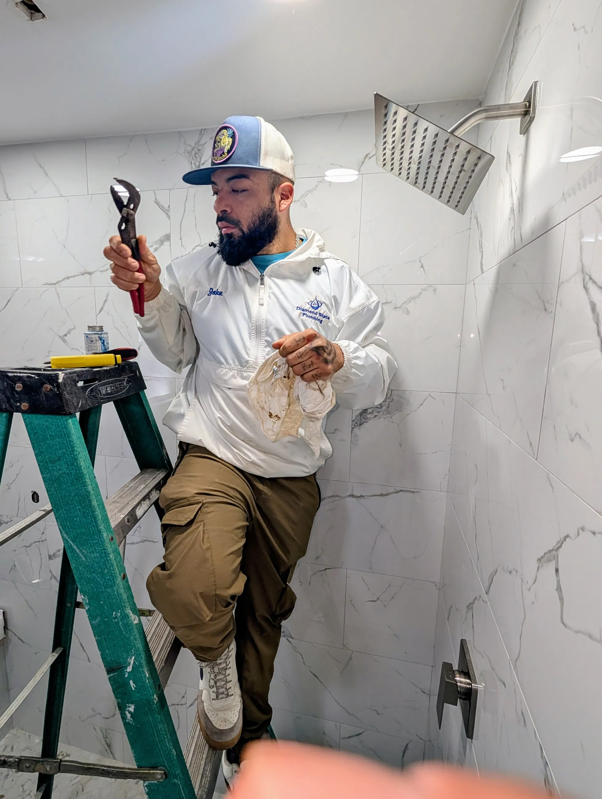 Diamond State Plumbing technician on ladder during shower head installation
