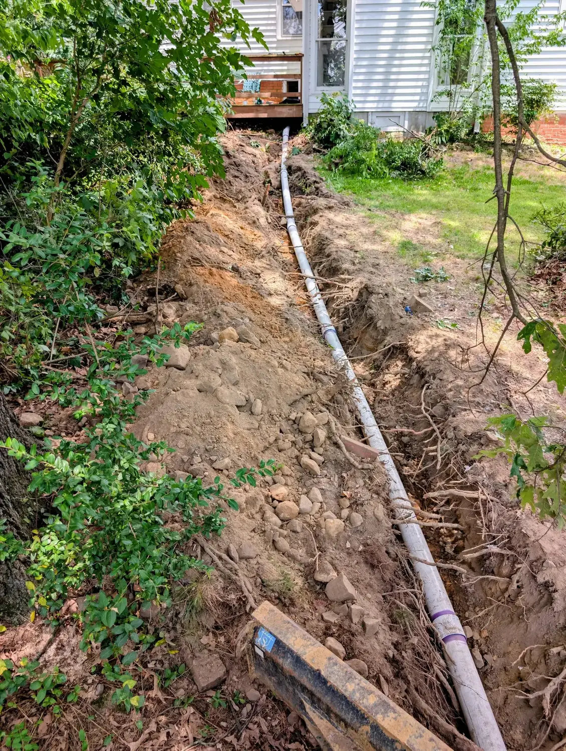 Drain line installation by Diamond State Plumbing showing PVC pipe in excavated trench
