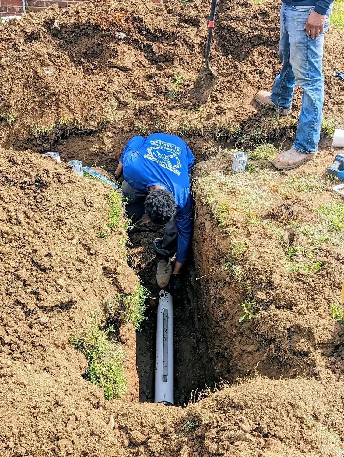 Diamond State Plumbing technician working in a trench on a sewer line